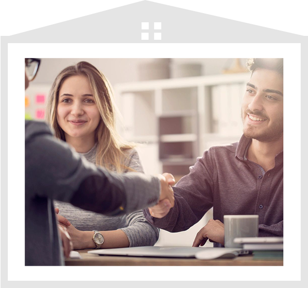 A man and woman shaking hands over a table.